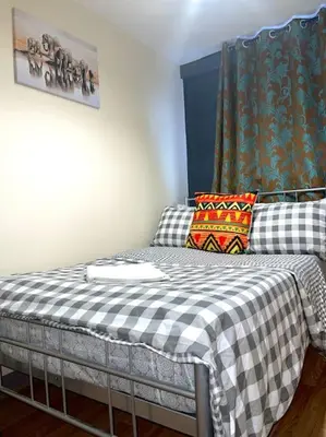 a bedroom with a bed with a checkered blanket at 12 Penn Gardens - Apart 1 in Friern Barnet