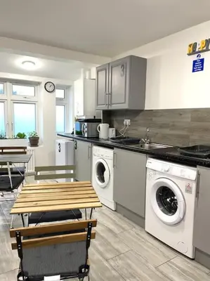 a kitchen with a washer and dryer and a table at 12 Penn Gardens - Apart 1 in Friern Barnet