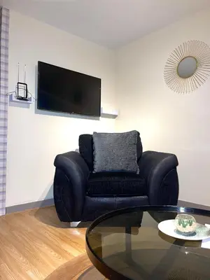 a living room with a black couch and a glass table at 12 Penn Gardens - Apart 1 in Friern Barnet