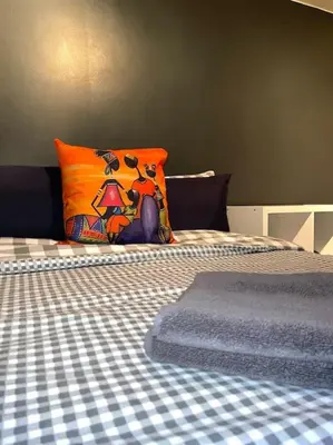 a bed with a checkered sheet and a pillow on it at 12 Penn Gardens - Apart 1 in Friern Barnet