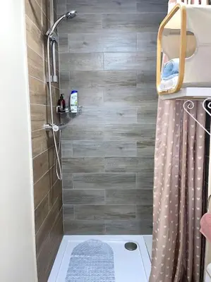 a bathroom with a shower with a wooden wall at 12 Penn Gardens Standard Room- 4 in Friern Barnet