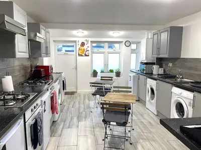 a kitchen with white appliances and tables and chairs at 12 Penn Gardens Standard Room- 4 in Friern Barnet