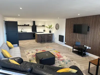 a living room with a couch and a kitchen at New 2 Bed Apartment in Royston High St in Royston