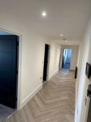 a hallway with white walls and wooden floors at New 2 Bed Apartment in Royston High St in Royston