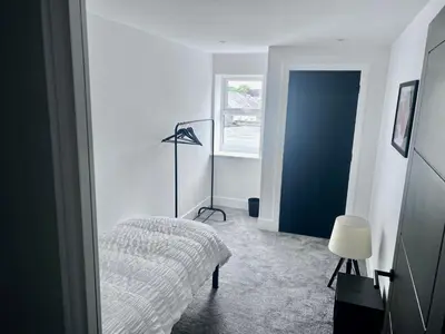 a white bedroom with a bed and a blue door at New 2 Bed Apartment in Royston High St in Royston
