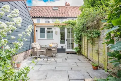 a patio with a table and chairs in front of a house at Angel Cottage, Wenhaston in Halesworth