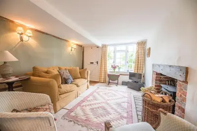 a living room with a couch and a fireplace at Angel Cottage, Wenhaston in Halesworth