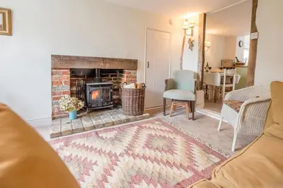 a living room with a fireplace and a couch at Angel Cottage, Wenhaston in Halesworth