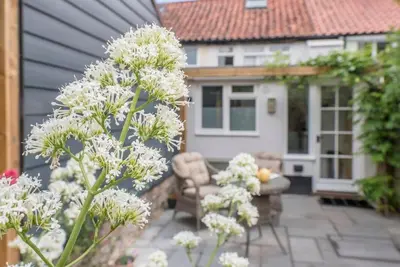 a garden with white flowers in front of a house at Angel Cottage, Wenhaston in Halesworth