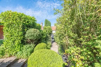 a garden with bushes and trees and a house at Angel Cottage, Wenhaston in Halesworth