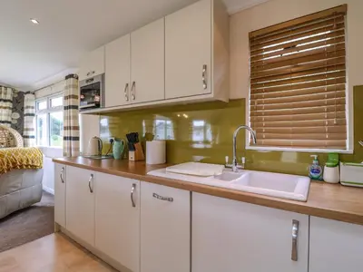 a kitchen with white cabinets and a sink at Owls Retreat, Lodge 11 in Aldeburgh