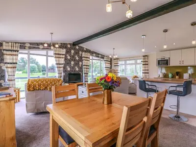 a kitchen and living room with a wooden dining room table at Owls Retreat, Lodge 11 in Aldeburgh