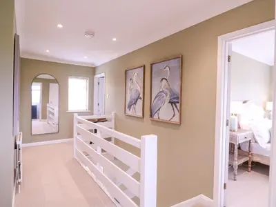 a home hallway with a white rail and paintings on the wall at The Farmhouse in Clacton-on-Sea
