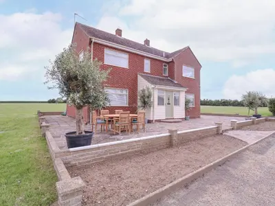 a brick house with a table and chairs in the yard at The Farmhouse in Clacton-on-Sea