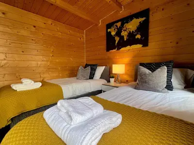 two beds in a room with wooden walls at Duchess Lodge In Colchester 1BR,Couples, Contractors,Business Travellers, Free WIFI, Secure Parking in Colchester