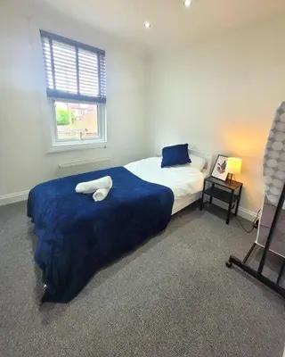 a bedroom with a bed with a blue blanket and a window at 3-Bed, Sleeps 6, 1 Bath, Parking, WiFi in Halstead