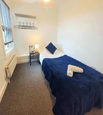 a bedroom with a large bed with a blue blanket at 3-Bed, Sleeps 6, 1 Bath, Parking, WiFi in Halstead