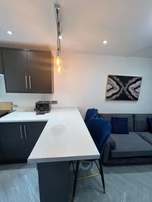 a kitchen and living room with a table and a couch at Stylish Flat in London in Harold Wood