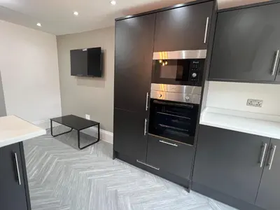 a kitchen with black cabinets and an oven at Stylish Flat in London in Harold Wood