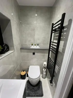 a bathroom with a white toilet and a bath tub at Stylish Flat in London in Harold Wood
