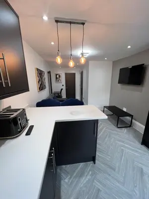 a room with a white counter and a living room at Stylish Flat in London in Harold Wood