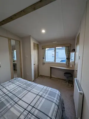 a bedroom with a bed and a window and a desk at Van-Tastic 6 berth static in Felixstowe