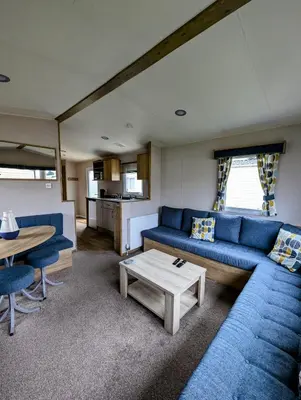 a living room with a blue couch and a table at Van-Tastic 6 berth static in Felixstowe