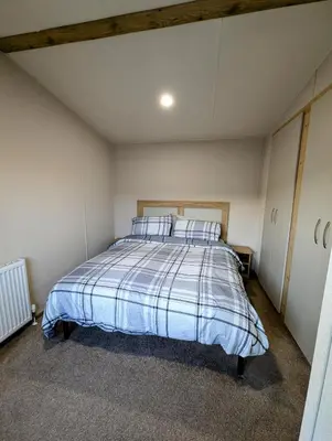 a bedroom with a bed with blue and white sheets at Van-Tastic 6 berth static in Felixstowe