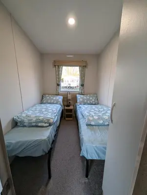 two beds in a small room with a window at Van-Tastic 6 berth static in Felixstowe