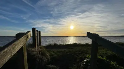 a sunset over the water with a wooden fence at Cosy 2 bed cottage in beautiful Orford in Orford