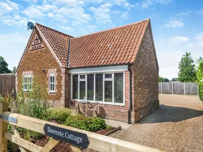 a brick house with a sign in front of it at Dovecote Cottage in Downham Market