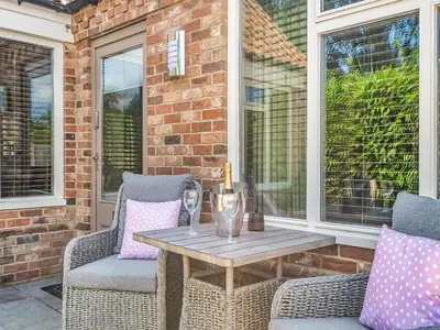 a patio with a table and chairs on a porch at Dovecote Cottage in Downham Market