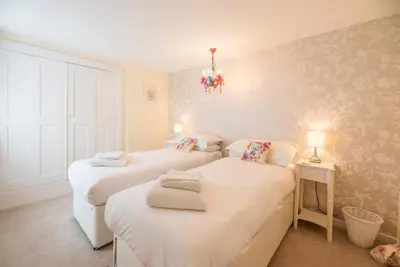 a bedroom with two beds and a chandelier at Oriel Cottage, Aldeburgh in Aldeburgh