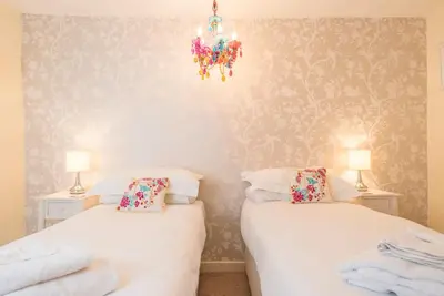 two twin beds in a room with a chandelier at Oriel Cottage, Aldeburgh in Aldeburgh