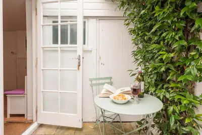 a white table with a glass of wine and a book at Oriel Cottage, Aldeburgh in Aldeburgh