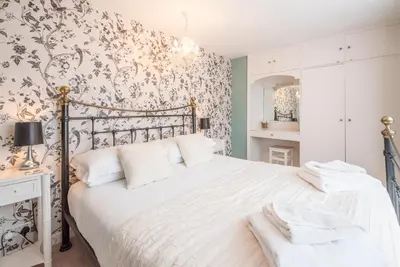 a bedroom with a white bed with a floral wallpaper at Oriel Cottage, Aldeburgh in Aldeburgh