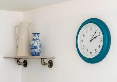 a blue clock on a wall with a vase on a shelf at The Keep - Framlingham in Framlingham