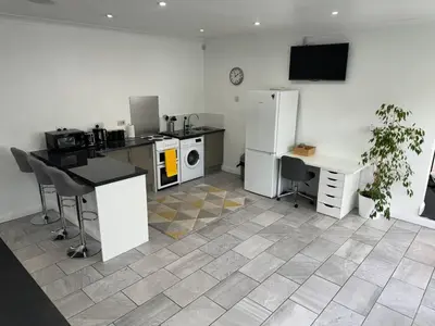 a kitchen with a refrigerator and a table and a desk at Spacious private cinema guest house in Brentwood