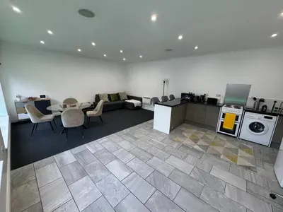 a living room with a couch and a table and a kitchen at Spacious private cinema guest house in Brentwood
