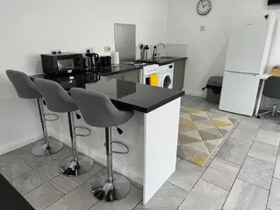 a kitchen with a counter and two bar stools at Spacious private cinema guest house in Brentwood