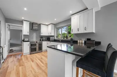 a kitchen with white cabinets and a black counter top at 10 Holly Close in Westley