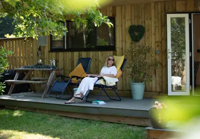 a woman sitting in chairs on the porch of a house at Luxury Chestnut Lodge with Hot Tub and Games Room in Toppesfield