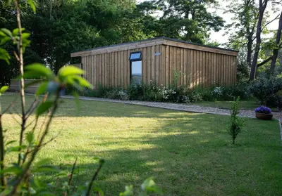a small wooden shed in a yard with a lawn at Luxury Chestnut Lodge with Hot Tub and Games Room in Toppesfield