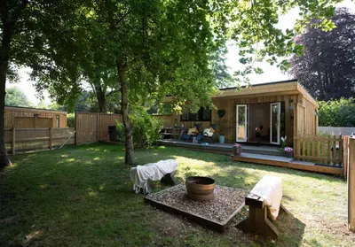 a backyard with a small wooden house with a tree at Luxury Chestnut Lodge with Hot Tub and Games Room in Toppesfield