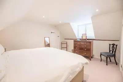 a white bedroom with a bed and a chair at 10 Angel Lane, Woodbridge in Woodbridge