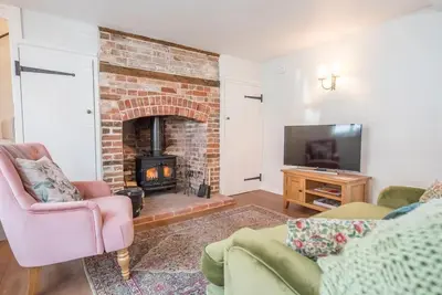 a living room with a brick fireplace and a tv at 10 Angel Lane, Woodbridge in Woodbridge
