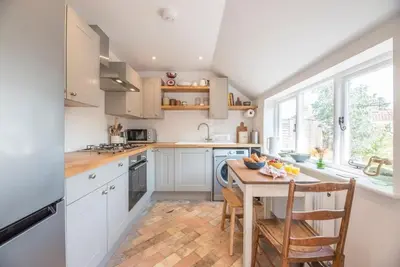 a kitchen with white cabinets and a wooden table at 10 Angel Lane, Woodbridge in Woodbridge