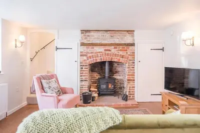a living room with a brick fireplace and a chair at 10 Angel Lane, Woodbridge in Woodbridge