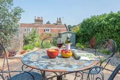 a table with a glass of wine and a bowl of fruit at 10 Angel Lane, Woodbridge in Woodbridge