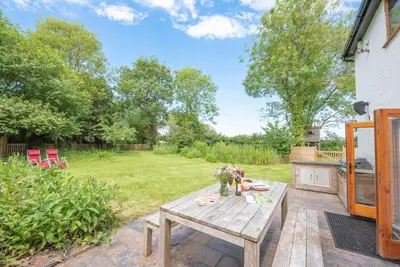 a patio with a wooden table in a yard at Little Swattesfield, Eye in Eye